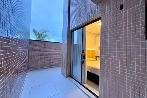 a bathroom with white tile walls and a glass door at Harmonie apto requintado | Centro | 200m do mar in Itapoa
