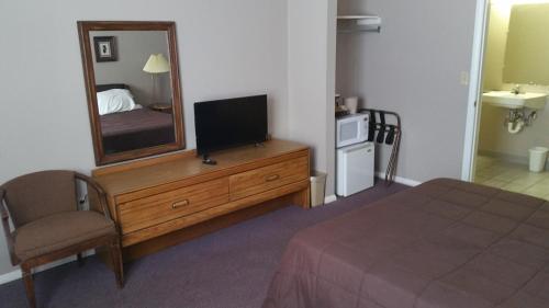 a bedroom with a television on a dresser with a mirror at Coach Stop Motel in Wellsboro