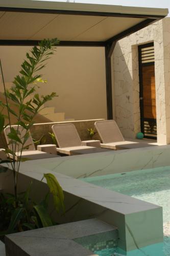 a pool with two lounge chairs next to a swimming pool at Hotel Boutique Kasa Sara in San Patricio Melaque
