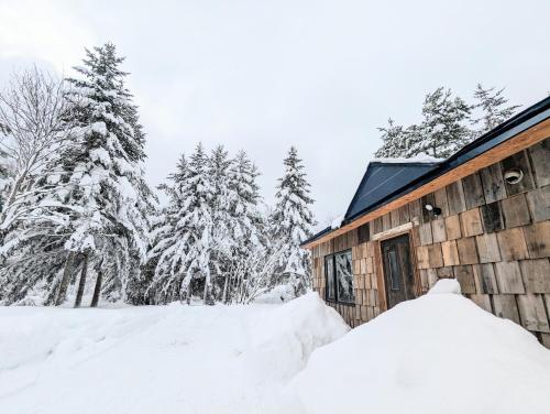 a pile of snow next to a cabin at 暮らす宿ソラプチ Sorapchi Cabin in Ochiai