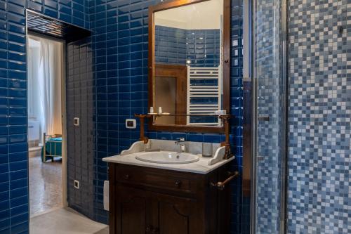 a blue tiled bathroom with a sink and a mirror at B&B del pozzo in Narni