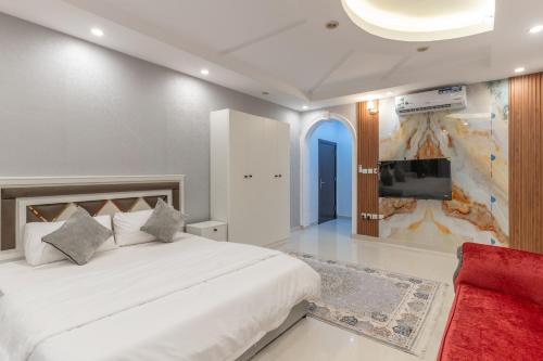 a bedroom with a large white bed and a tv at Jeddah Apartment in Jeddah