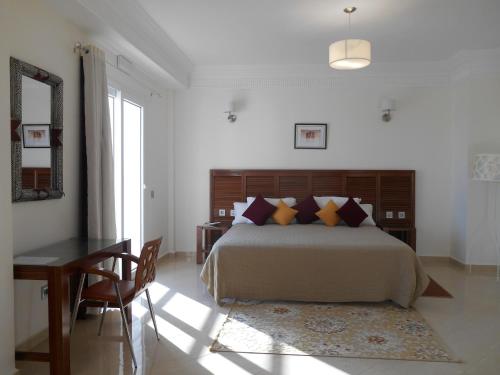 a bedroom with a bed and a table and a desk at Boutique Hôtel Albaraka in Dakhla