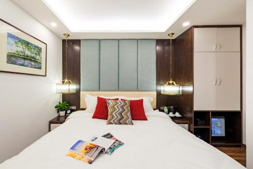 ein Schlafzimmer mit einem großen weißen Bett mit roten Kissen in der Unterkunft Splendid Hotel & Spa in Hanoi