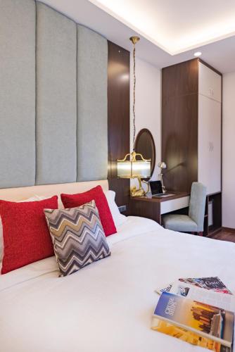 a bedroom with a white bed with red pillows and a desk at Splendid Hotel & Spa in Hanoi