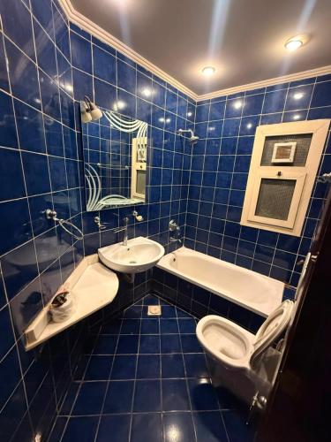 a blue tiled bathroom with a toilet and a sink at Porto Sokhna Aprtment Pool View - MR in Ain Sokhna