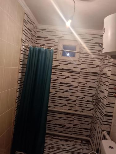 a bathroom with a shower with a blue shower curtain at House Ali in Klyuchi