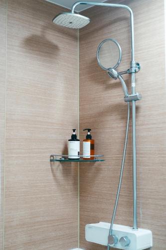 a shower with a shelf and two bottles on it at 솔향기펜션 in Hongcheon