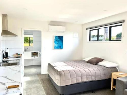 a white bedroom with a bed and a sink at Kerigold Secluded Chalets Motel in Kerikeri