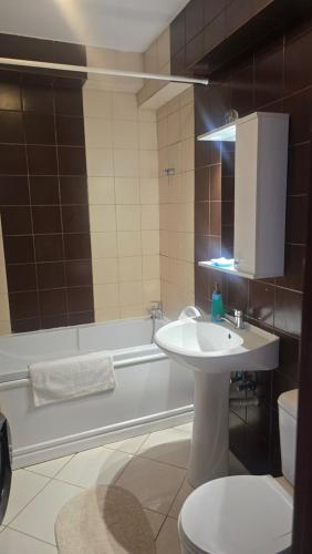 a bathroom with a sink and a toilet and a tub at Maritimo Apartment in Constanţa