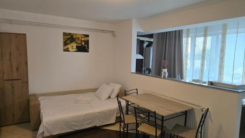 a bedroom with a bed and a table with chairs at Maritimo Apartment in Constanţa