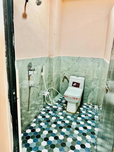 a bathroom with a toilet and a tiled floor at Avigat Kabir hotel sanwer in Sānwer