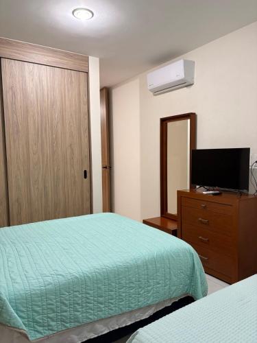 a hotel room with two beds and a television at The Hilltop Apartment in Guadalajara