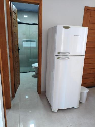 a white refrigerator in a room with a toilet at Morada dos eucaliptos in Capão da Canoa