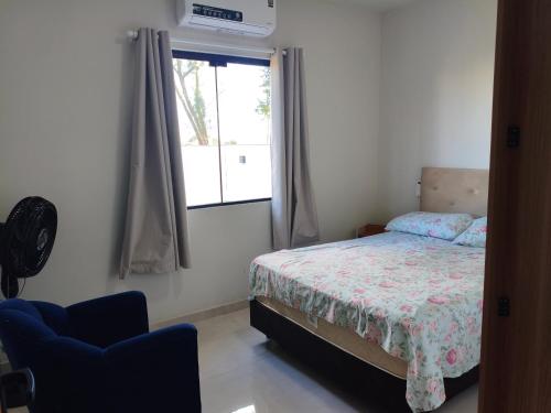 a bedroom with a bed and a chair and a window at Morada dos eucaliptos in Capão da Canoa