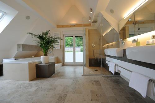 a bathroom with two sinks and a tub and a plant at Hotel Restaurant Jaegersteig in Bühl