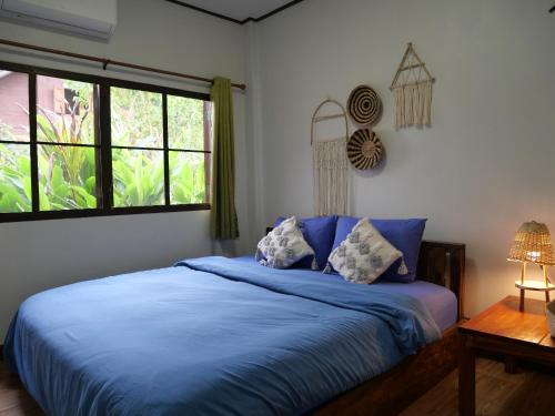 a bedroom with a bed with blue sheets and a window at นากลางดอย Naklangdoi in Ban Na Kham
