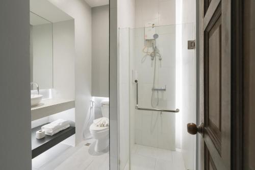 a white bathroom with a shower and a toilet at The Opium Chiang Mai in Chiang Mai