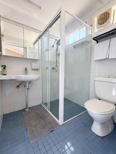 a bathroom with a shower and a toilet and a sink at Coffs Coastal Cabin, Central & Convenient in Coffs Harbour