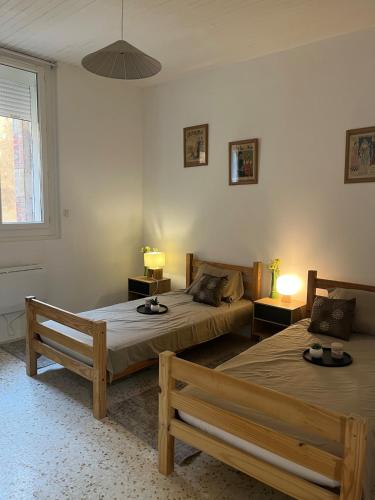 a bedroom with two beds and two benches in it at Le Cocon d aurélie in Thèzan-lès-Béziers
