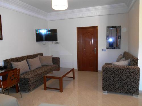 a living room with two couches and a tv at Boutique Hôtel Albaraka in Dakhla