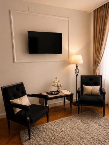 a living room with two chairs and a table and a tv at Mid Ultra Central Apartments, Self Check In in Oradea