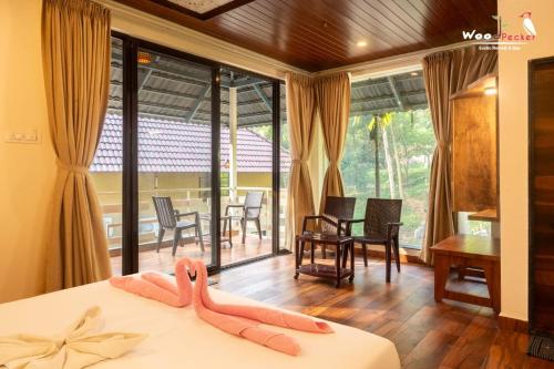 a room with a bed with two pink slippers on it at Green Nest Resorts in Malebennūr