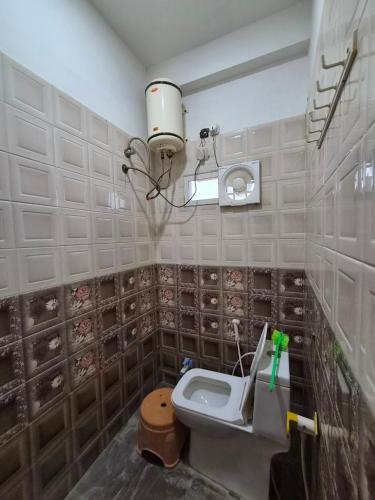 a bathroom with a toilet and a light on the wall at Serene Farmhouse in Nimarkheri