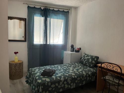 a bedroom with a bed and a window with blue curtains at Heaven Chambres chez l'habitant in Valergues