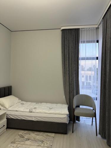 a bedroom with a bed and a chair and a window at Townhouse Atlantis Resort in Chetkoysu