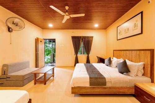 a bedroom with a bed and a couch and a fan at Rain Forest Jungle Stay in Kurandi