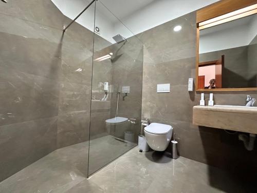 a bathroom with a shower and a toilet and a sink at Chateau Linza Resort in Tirana