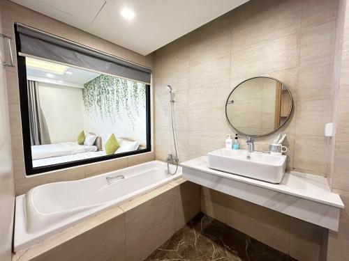 a bathroom with a tub and a sink and a mirror at FLC Sea Tower Quy Nhơn - View Biển in Quy Nhon