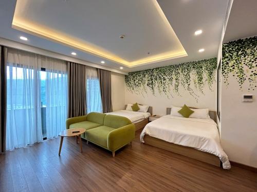 a hotel room with two beds and a green couch at FLC Sea Tower Quy Nhơn - View Biển in Quy Nhon