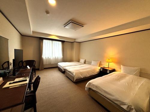 a hotel room with two beds and a desk at Hotel Karuizawa Elegance in Karuizawa
