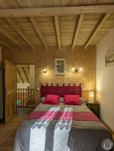 a bedroom with a large bed with red pillows at Le castillon in Marignac