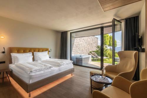 a bedroom with a bed and a large window at Gloriette Boutiquehotel in Soprabolzano
