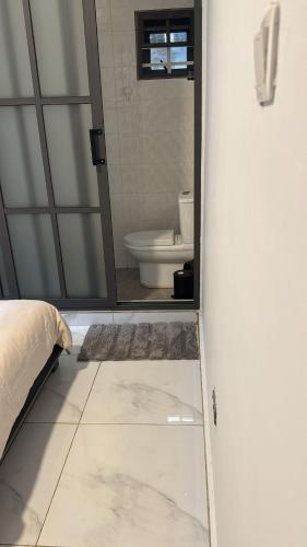 a bathroom with a toilet and a door with a mirror at Parkside City Apts in Accra
