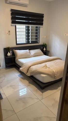 a large bed in a bedroom with a window at Parkside City Apts in Accra