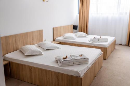 two beds in a hotel room with towels on them at Hotel Mercur in Eforie Sud
