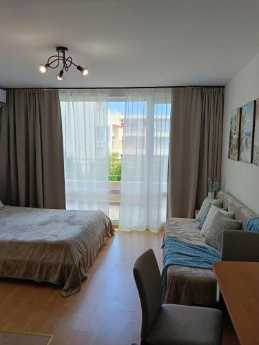 a bedroom with two beds and a chair and a window at Sea Breeze Studio at Fort Noks Resort in Sunny Beach