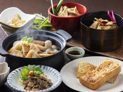 a table with two pots of food and plates of bread at KOKO HOTEL Himeji Castle in Himeji