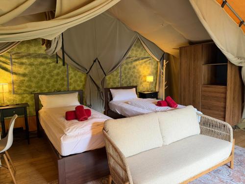a room with two beds and a couch in a tent at Glamping Resort Rio Vantone in Crone
