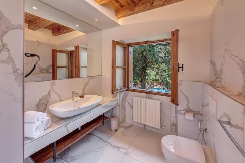 a bathroom with a sink and a toilet and a window at Hotel Rosa delle Alpi in Esino Lario