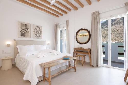 a white bedroom with a bed and a table at Aurum Suites Sifnos in Kamares