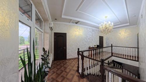 a hallway with a staircase and a chandelier at ESAL House in Karakol