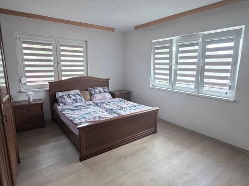 a bedroom with a bed and two windows at Sweet Home in Tuzla