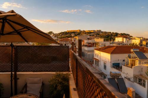 a balcony with an umbrella and some buildings at Old Town Rhapsody, Cosy 2-Floor Home with Rooftop Bathtub, BBQ & Lounge Under Sun Umbrellas in Rethymno