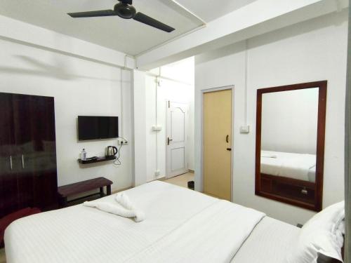 a white bedroom with a bed and a mirror at Hotel Zirora in Ziro
