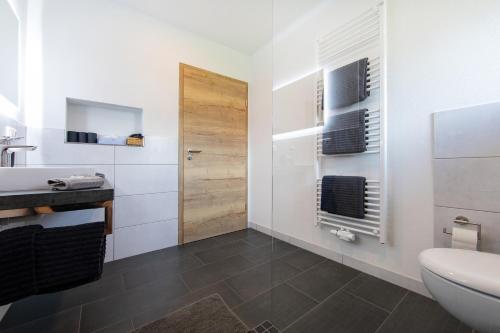 a white bathroom with a sink and a toilet at Appartementhaus EifelAdventures in Berlingen